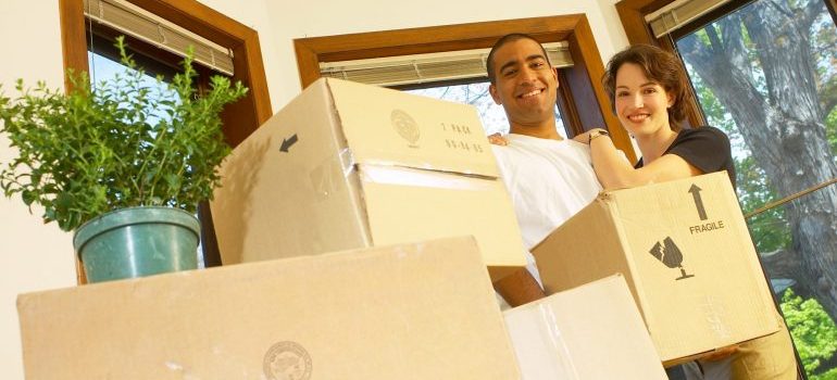 An image of a couple surrounded by moving boxes, happy with the Manhattan moving services they received.